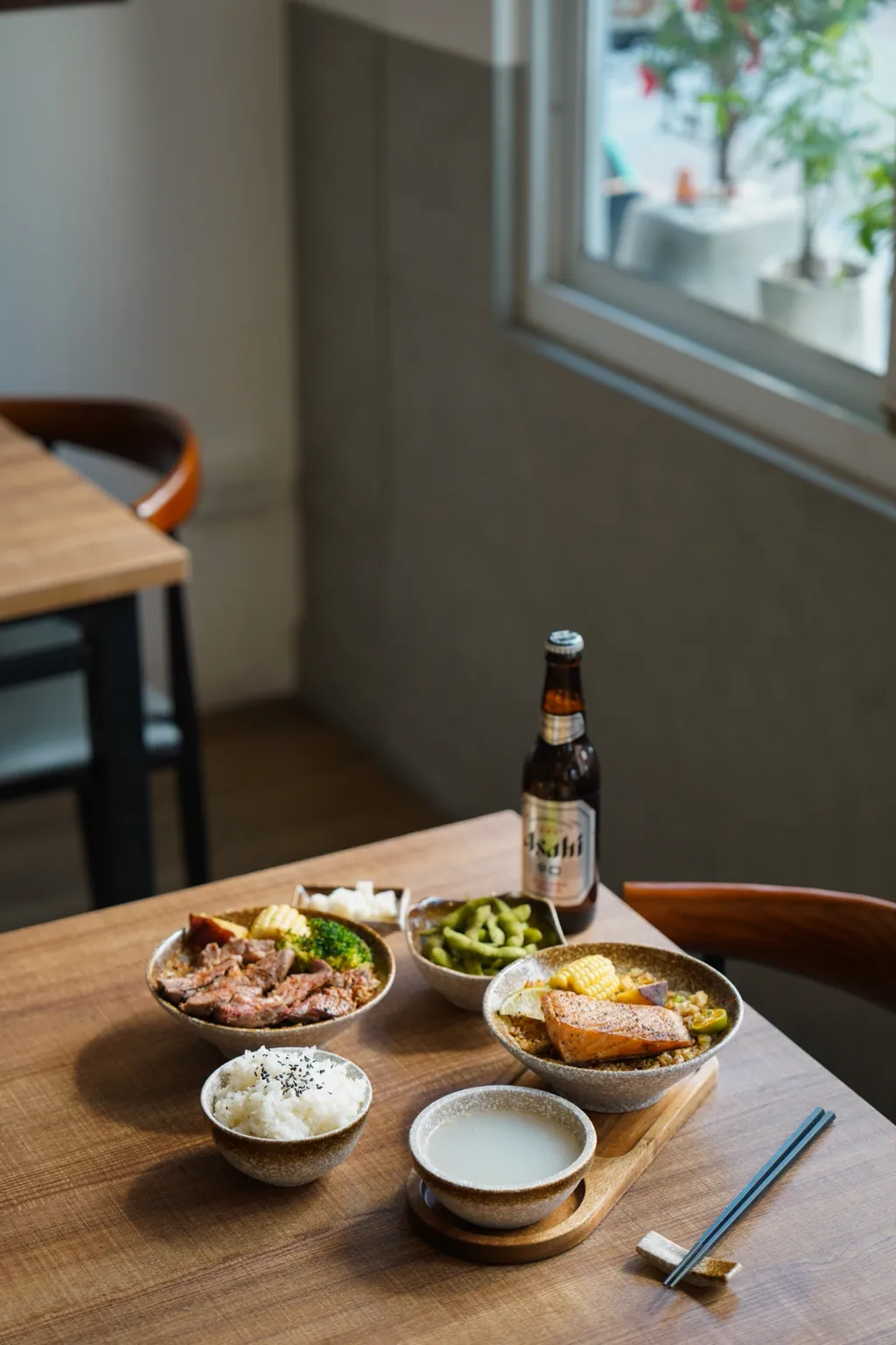 A set meal on a wooden table: fried rice, soup, side dishes and a chopstick rest