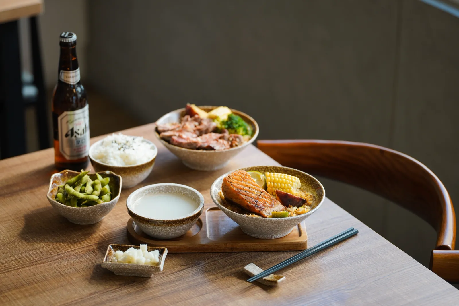 Two fried rice sets, soup bowls and beer on a wooden table in the afternoon light