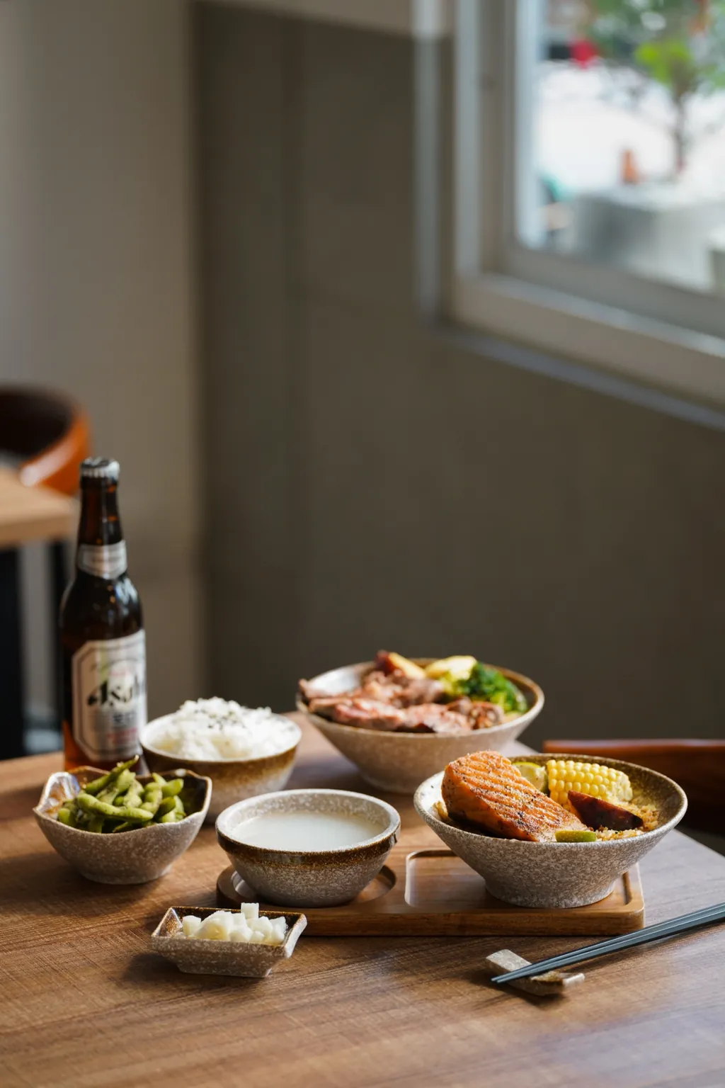 A fried rice set and a bottle of beer on a wooden table by the window