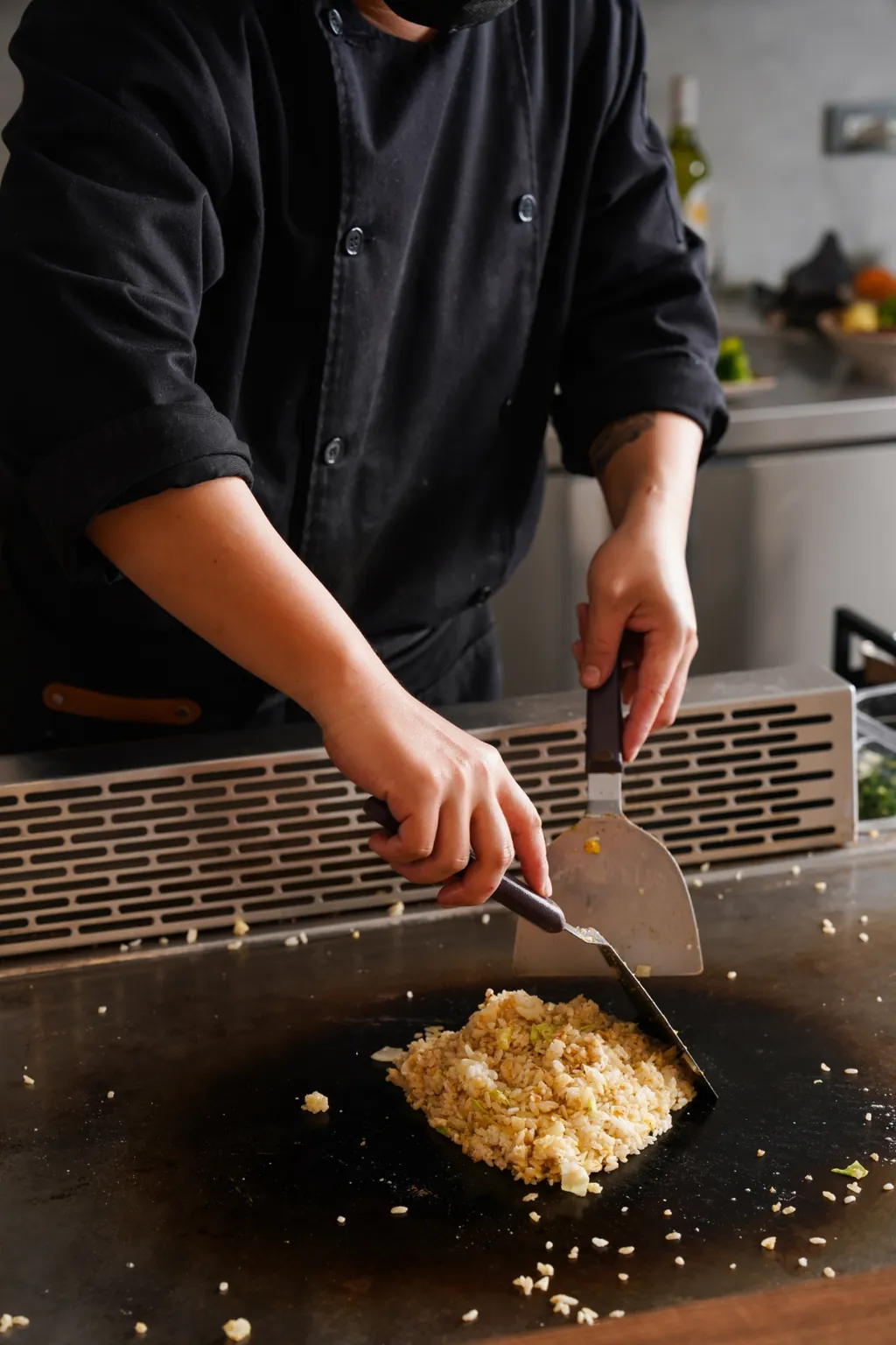 A chef gathering the finished fried rice into one portion