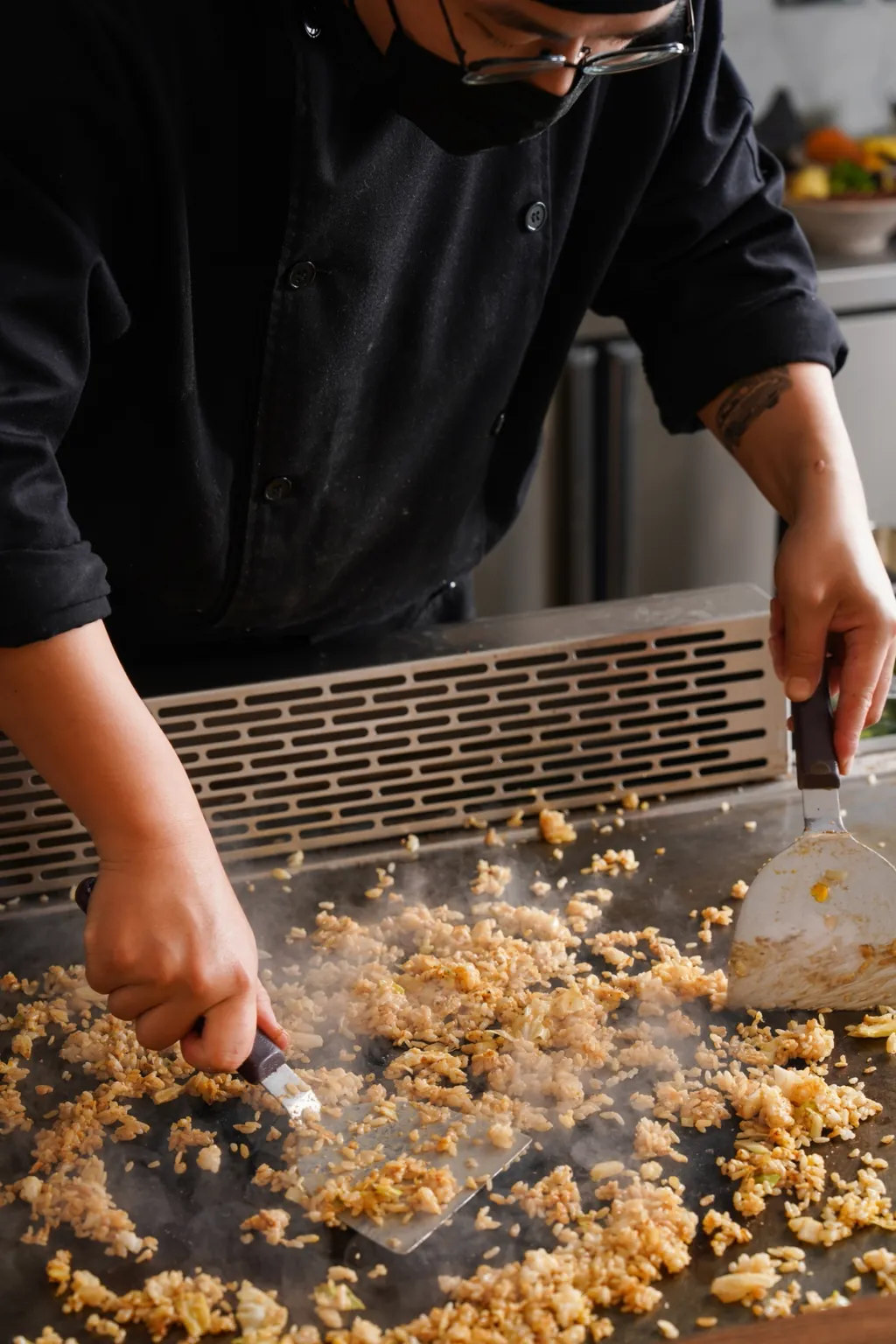 Rice hitting the hot griddle as steam rises